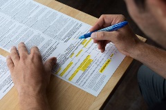 A male completing a paper Voter Registration form with a pen