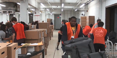 A group of people wheeling carts and boxes around the Board of Elections warehouse on Election Night